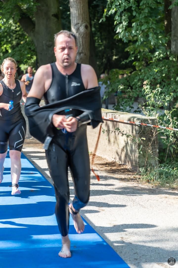 Een man in een wetsuit rent op een blauwe loper