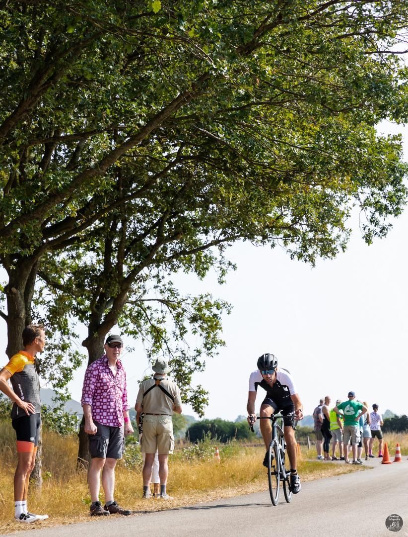 Een groep mensen kijkt naar een man die op een fiets over de weg rijdt.