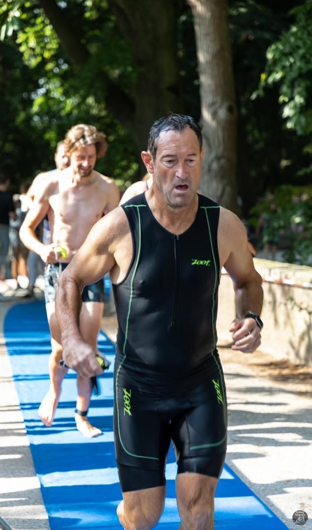 Een man in een wetsuit rent op een blauwe mat.