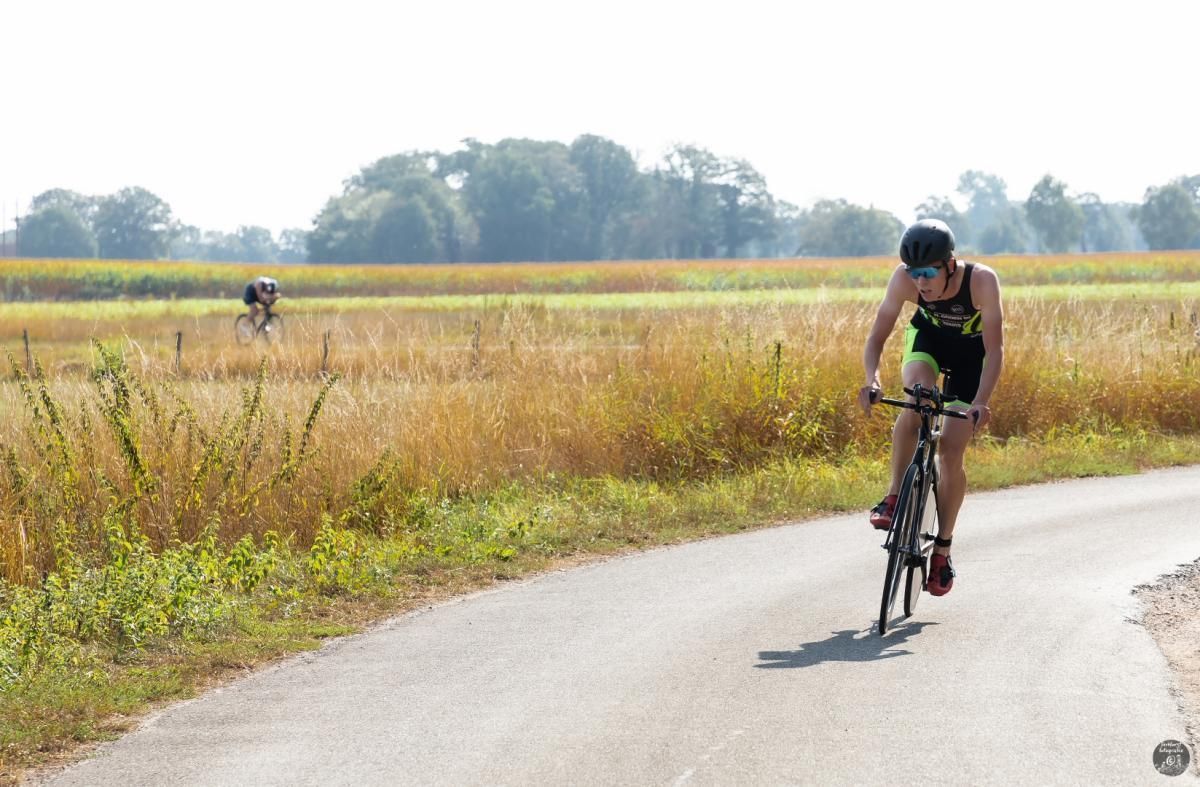 Een man fietst over een weg naast een veld.