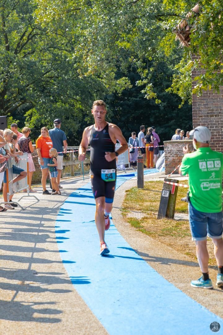 Een man rent op een blauwe baan voor een menigte mensen.