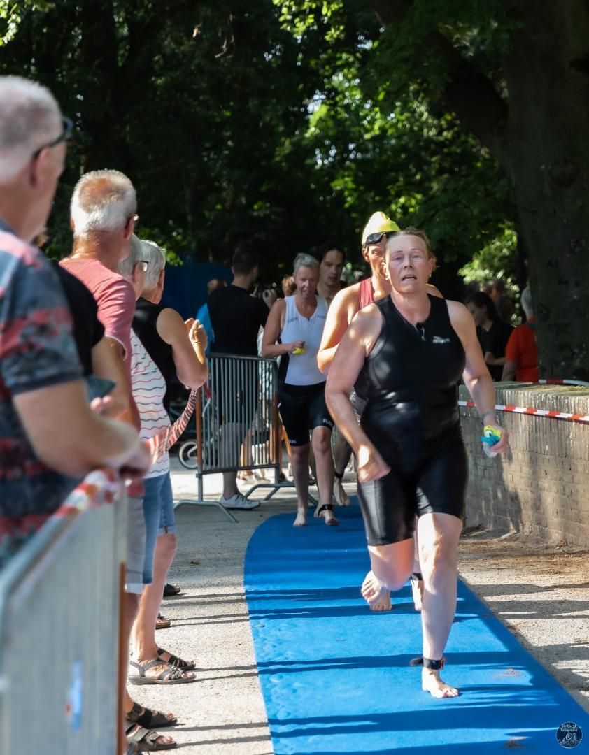 Een groep mensen kijkt naar een vrouw die op een blauwe baan rent