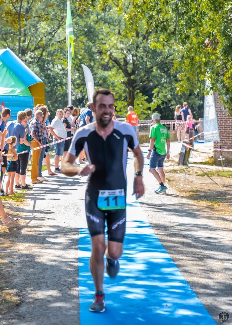 Een man rent over een blauwe loper met het nummer 11 op zijn startnummer.