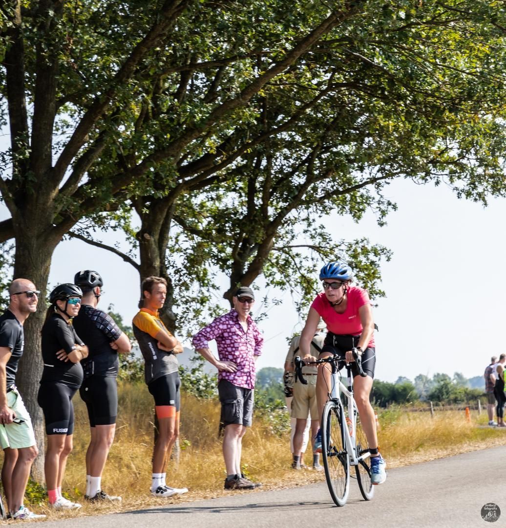 Een groep mensen kijkt naar een fietser op de weg