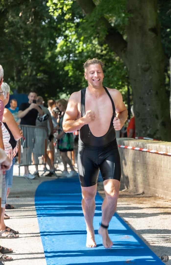 Een man in een wetsuit rent over een blauwe loper.