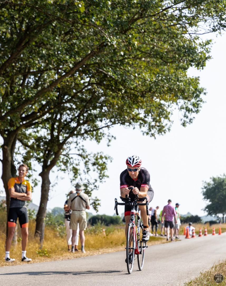 Een man met een helm rijdt op een fiets over een weg
