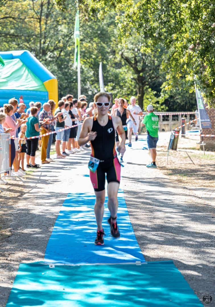 Een vrouw rent een marathon op een blauwe loper.