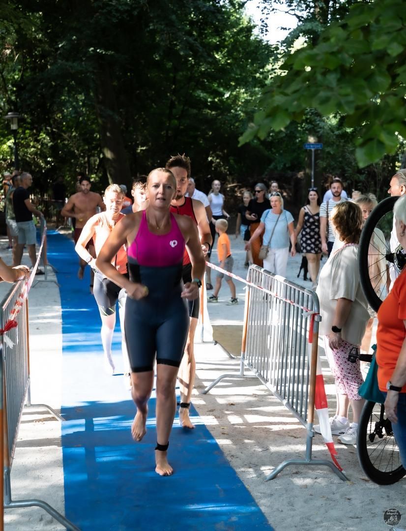 Een vrouw in een roze tanktop rent op een blauwe loper