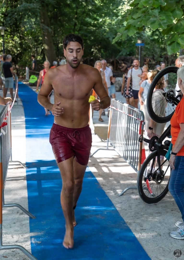 Een man zonder shirt rent over een blauwe loper