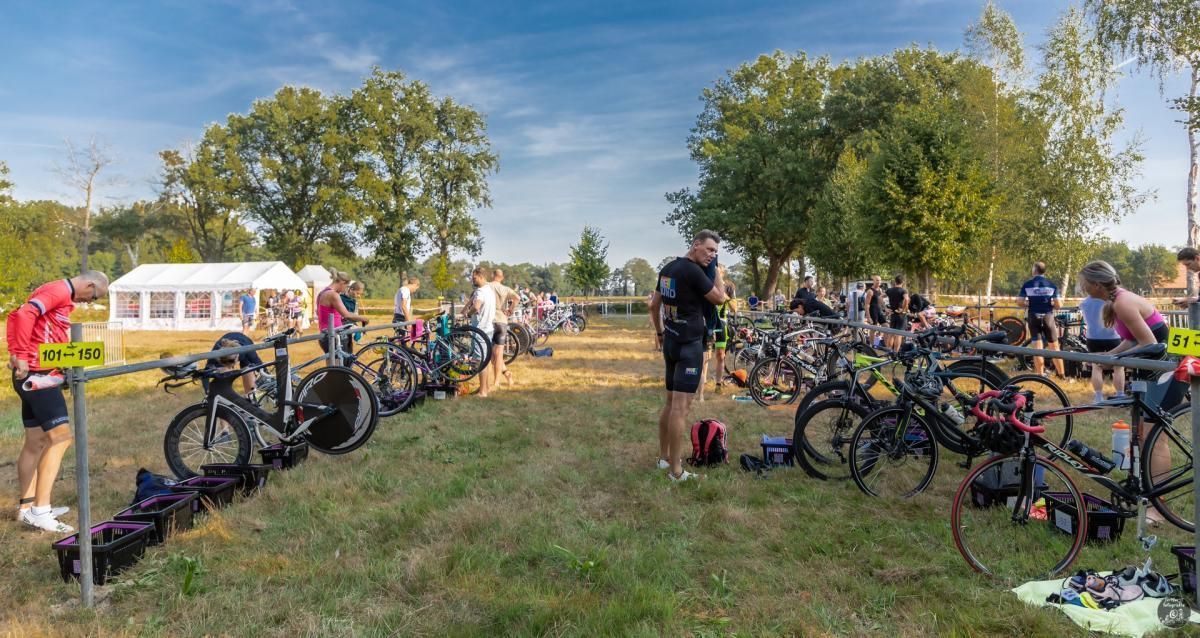 Een groep mensen staat rond fietsen in een veld.