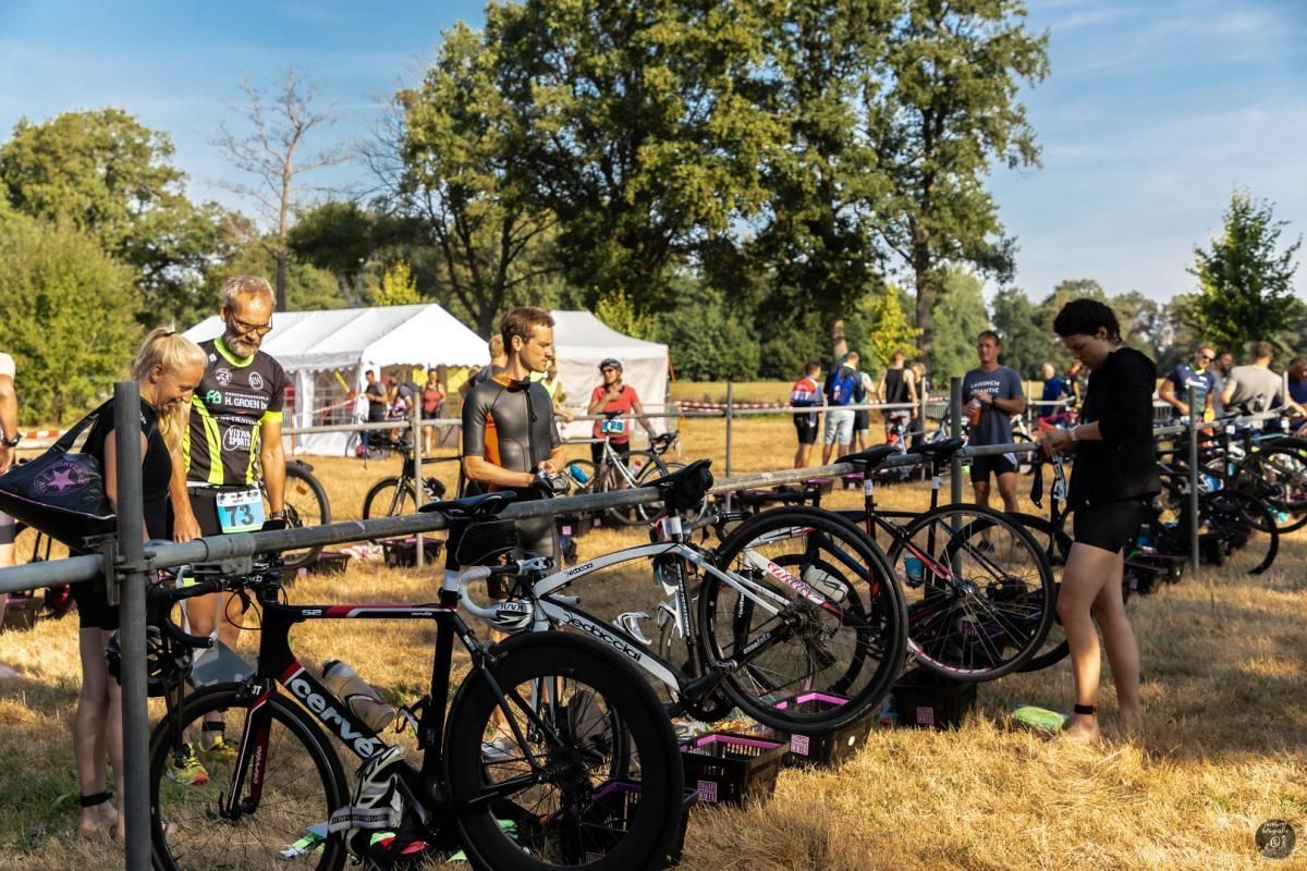 Een groep mensen staat rond fietsen in een veld.