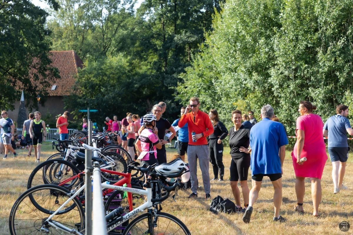 Een groep mensen staat rond fietsen in een park.