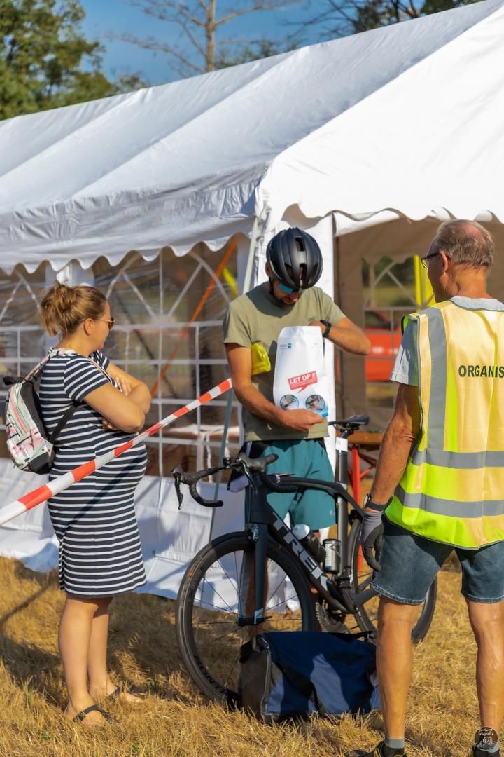 Een groep mensen staat voor een tent en praat met elkaar.