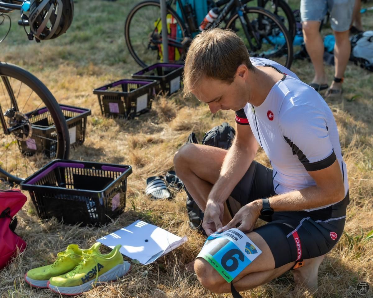 Een man knielt in het gras met een nummer 6 op zijn been.