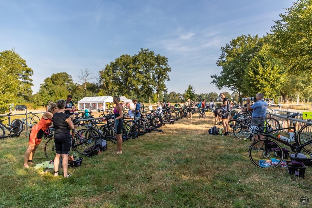Een groep mensen staat in een veld met fietsen.