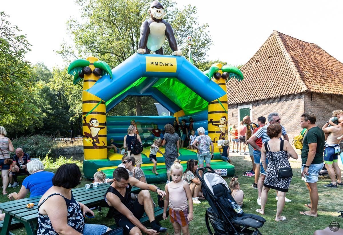 Een groep mensen speelt in een springkussen met een aap erbovenop.