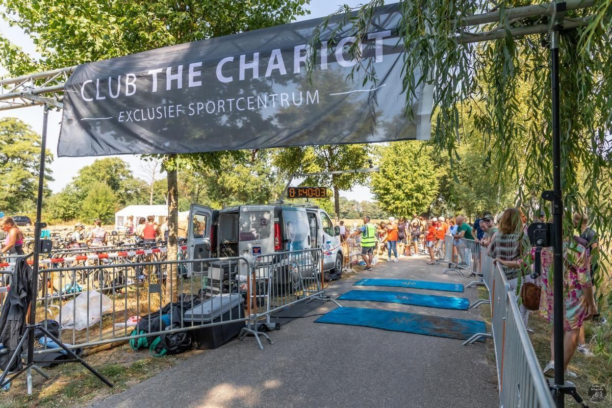 Een groep mensen staat voor een bord met de tekst 'Club The Charlie'.