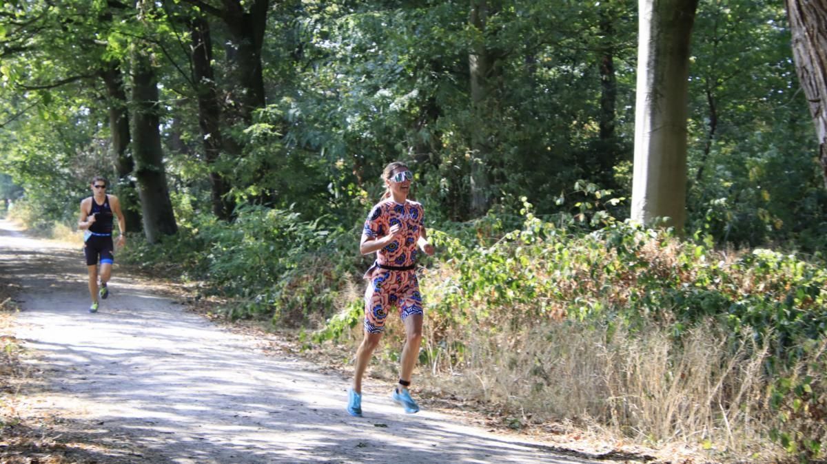 Twee mensen rennen over een pad in het bos.