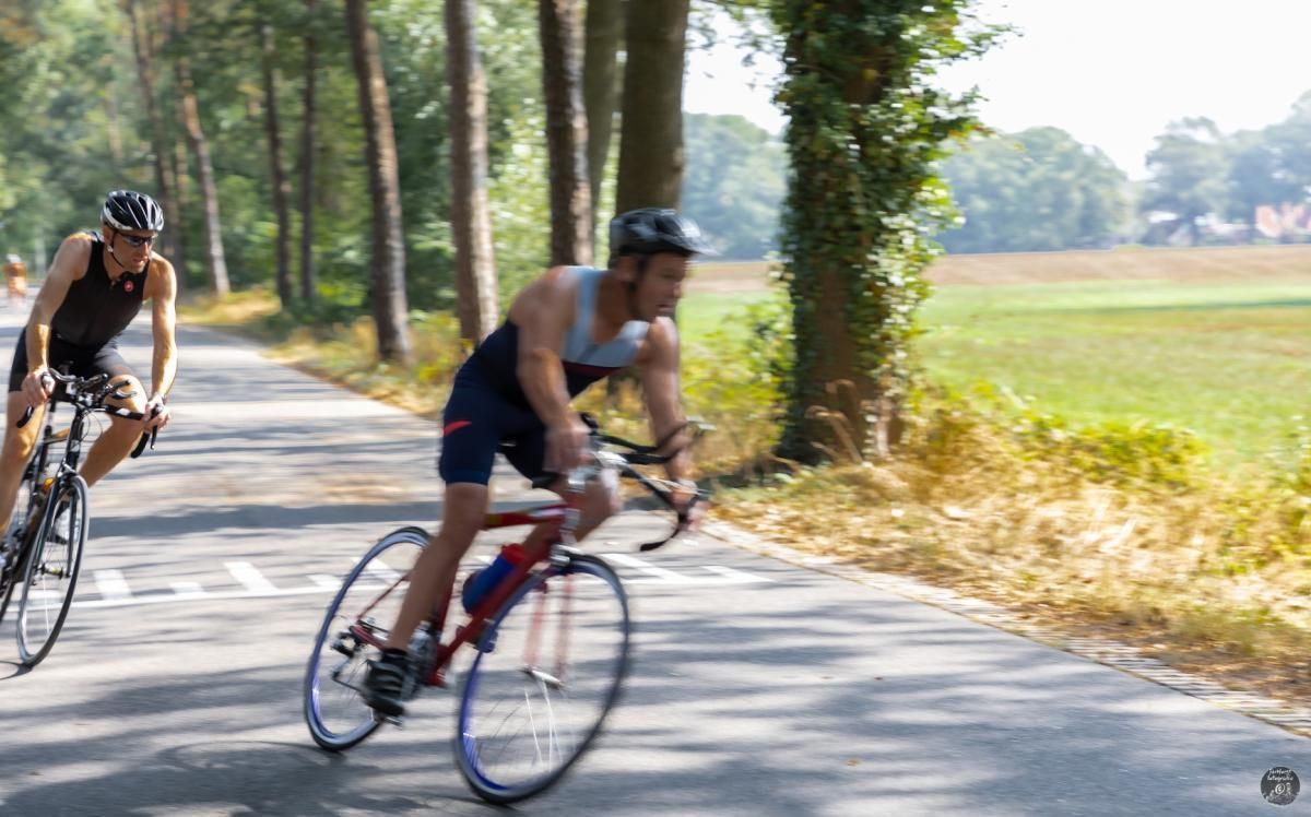 Twee mannen fietsen over een weg.