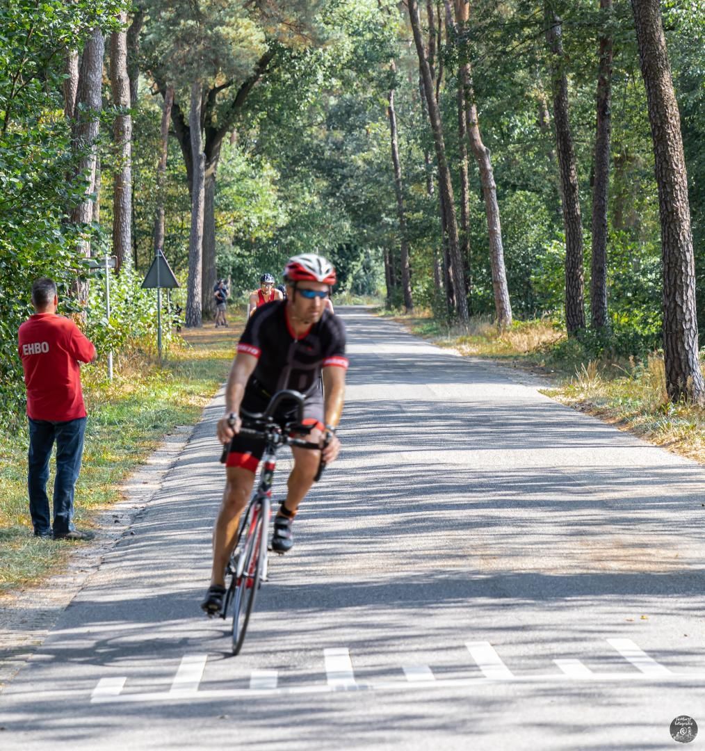 Een man fietst over een weg in het bos.