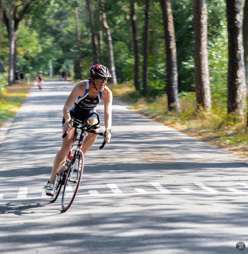 Een vrouw met een helm rijdt op een fiets over een weg