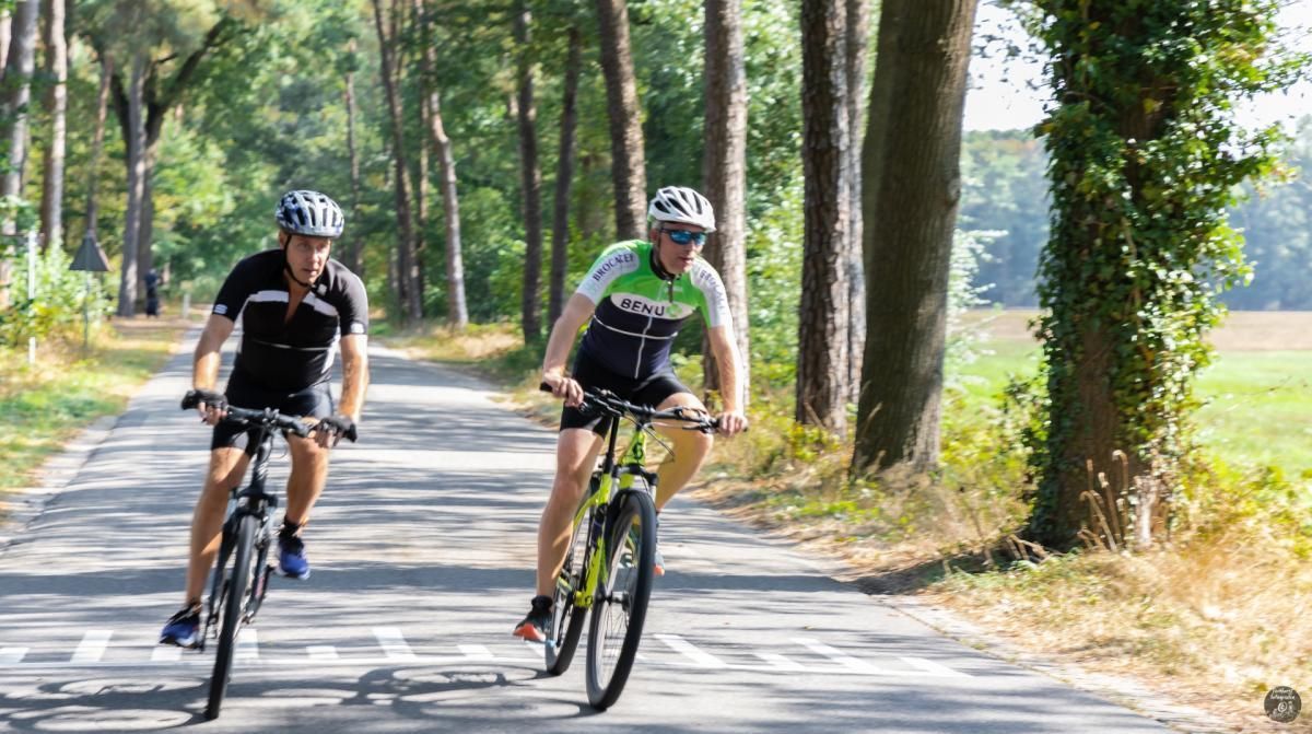Twee mensen fietsen over een landweg.
