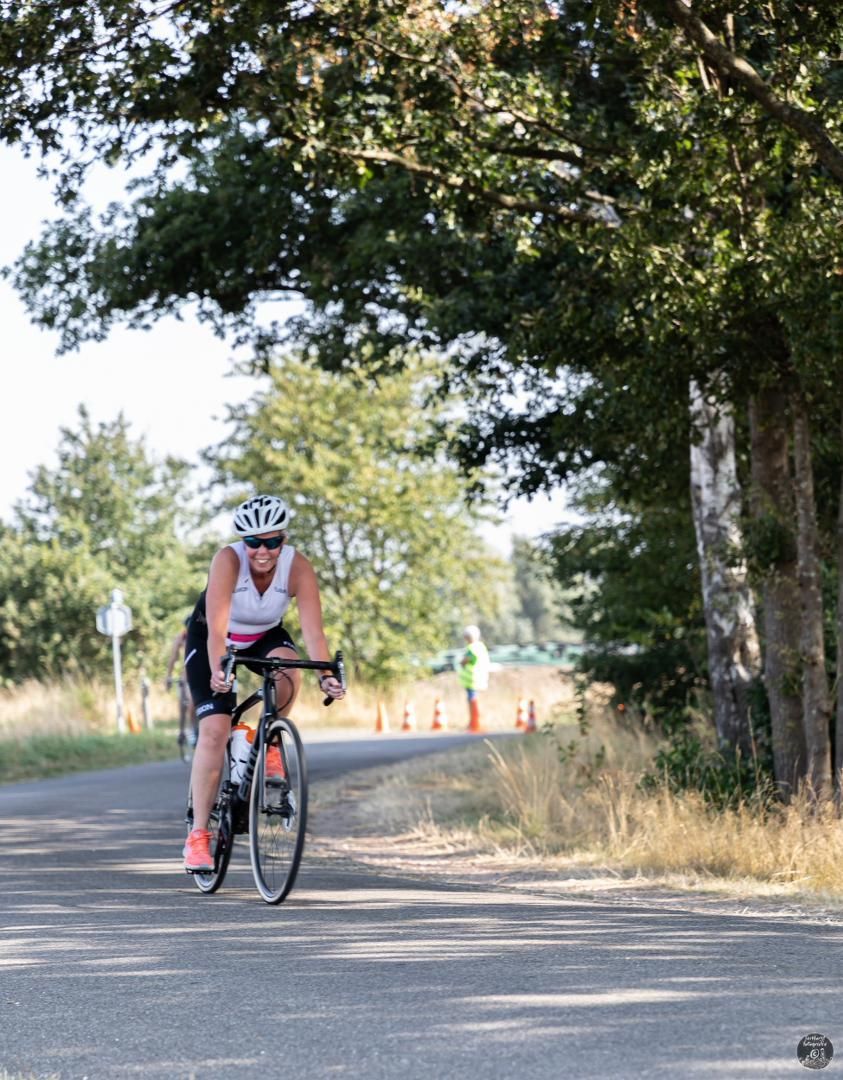 Een persoon fietst over een weg met bomen op de achtergrond