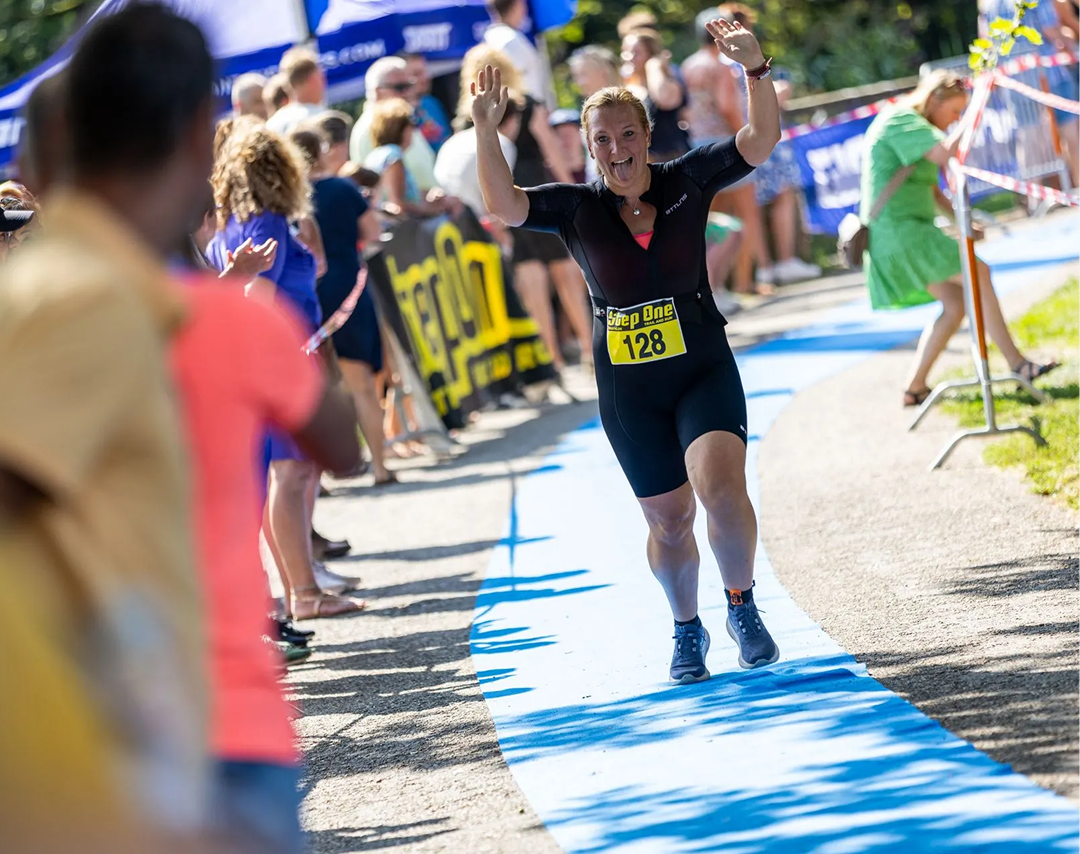 Een vrouw loopt een marathon op een blauwe loper.