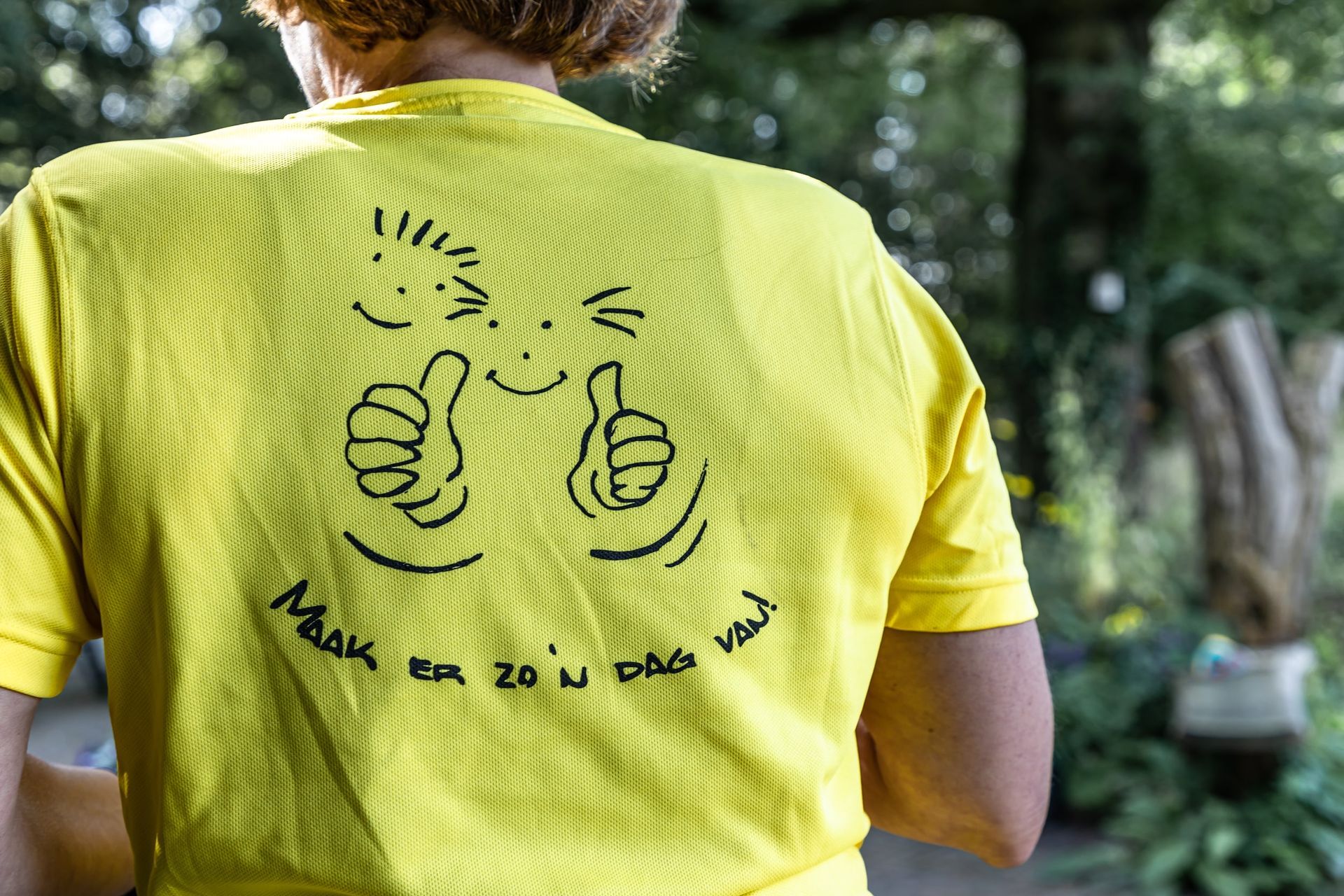 Een persoon draagt ​​een geel T-shirt met een cartoongezicht erop.