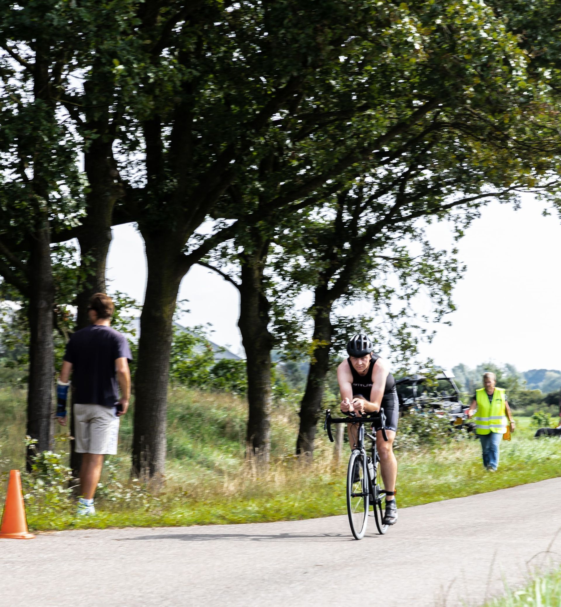 Een man fietst over een weg met bomen op de achtergrond