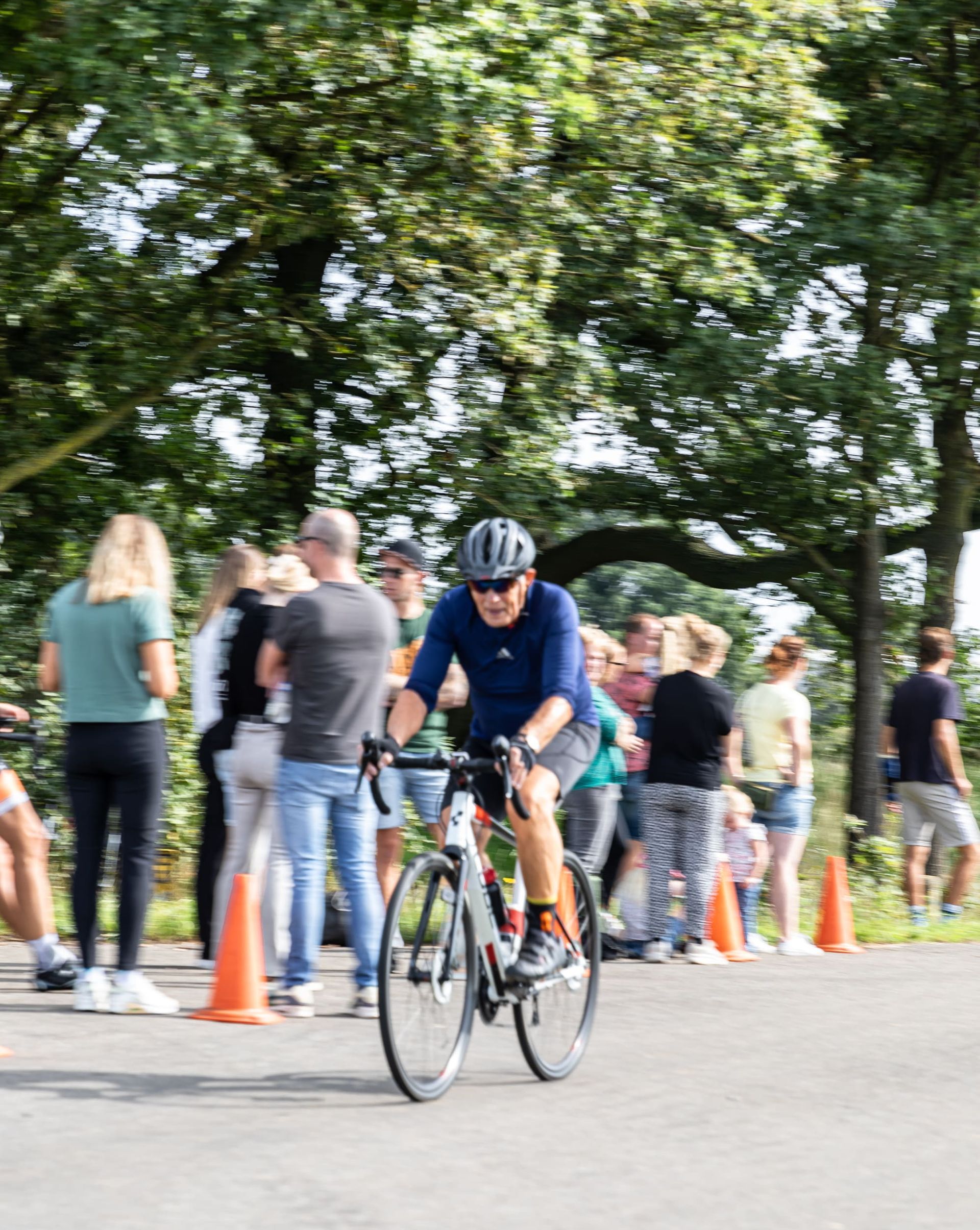 Een man fietst over een weg voor een menigte mensen.