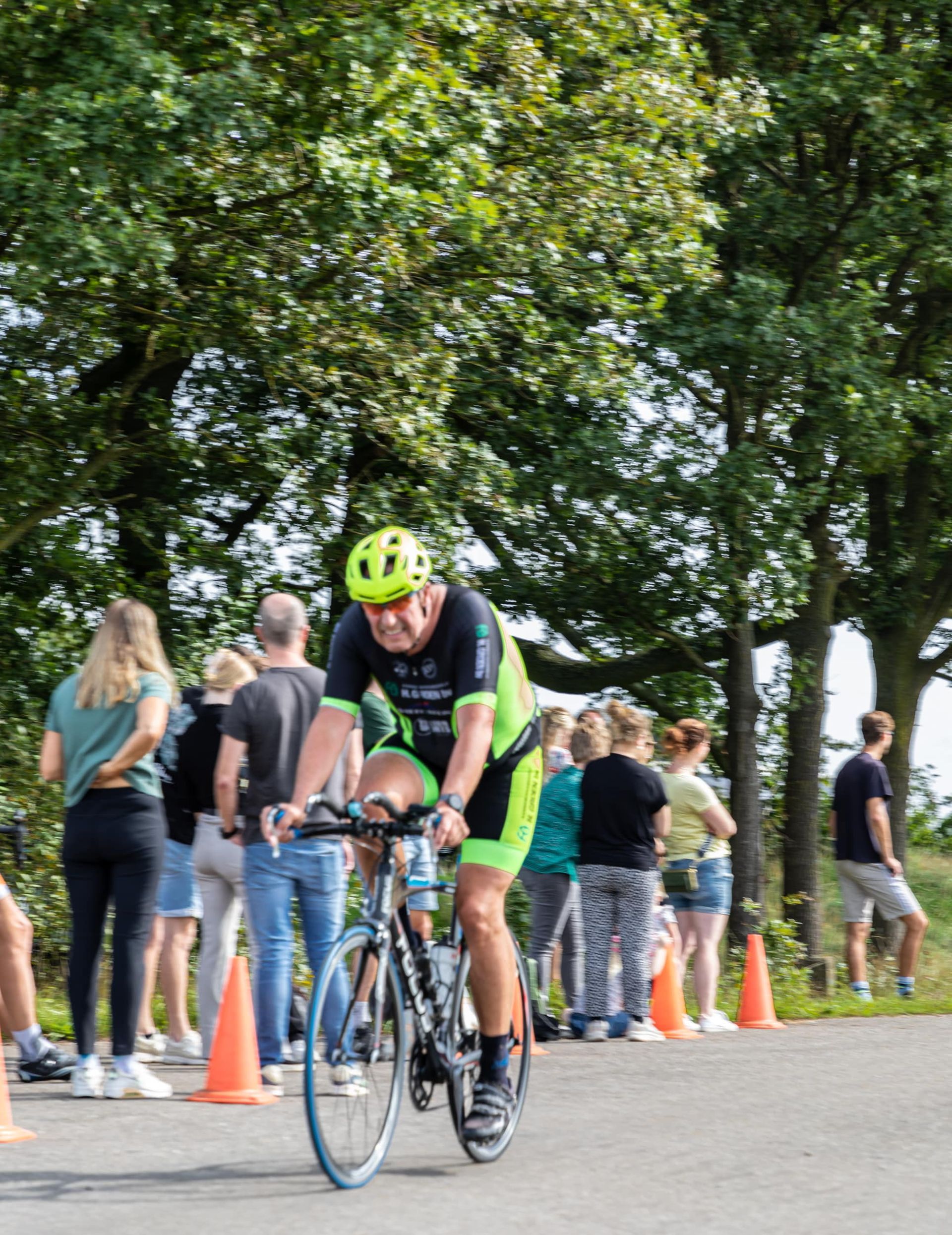 Een man met een helm rijdt op een fiets over de weg.