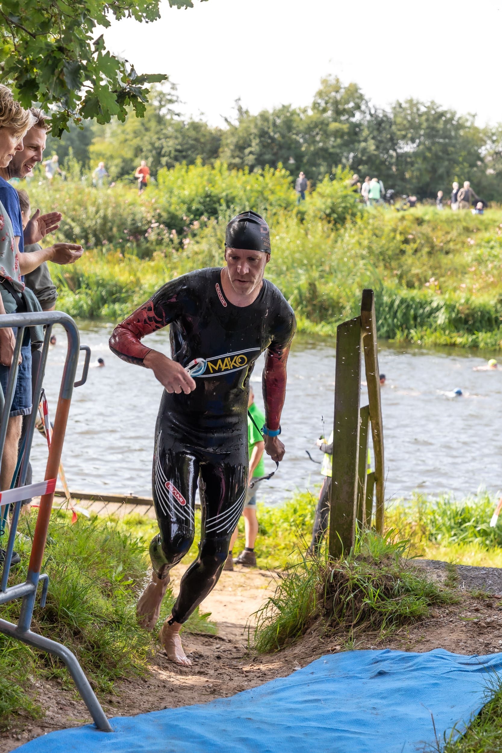 Een man in een wetsuit rent naar een watermassa.