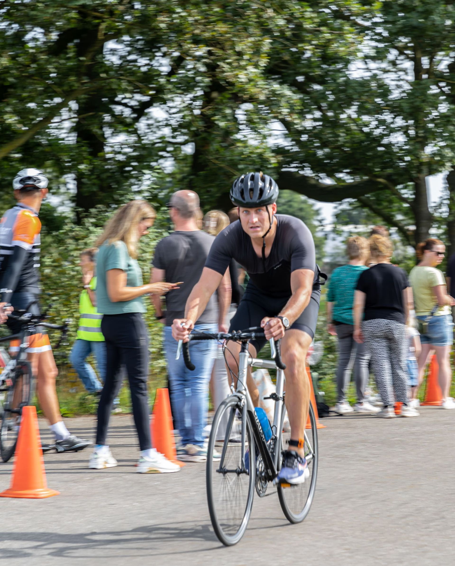 Een man met een helm rijdt op een fiets over de weg.