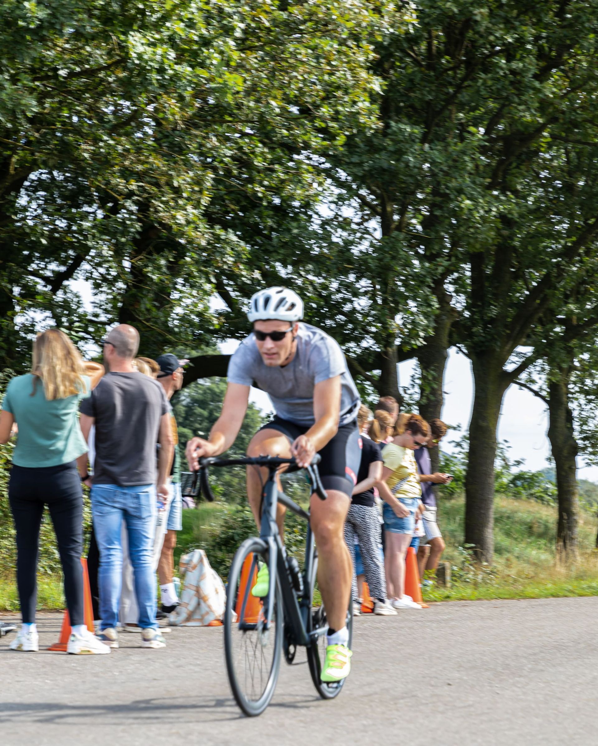 Een man met een helm rijdt op een fiets over de weg.