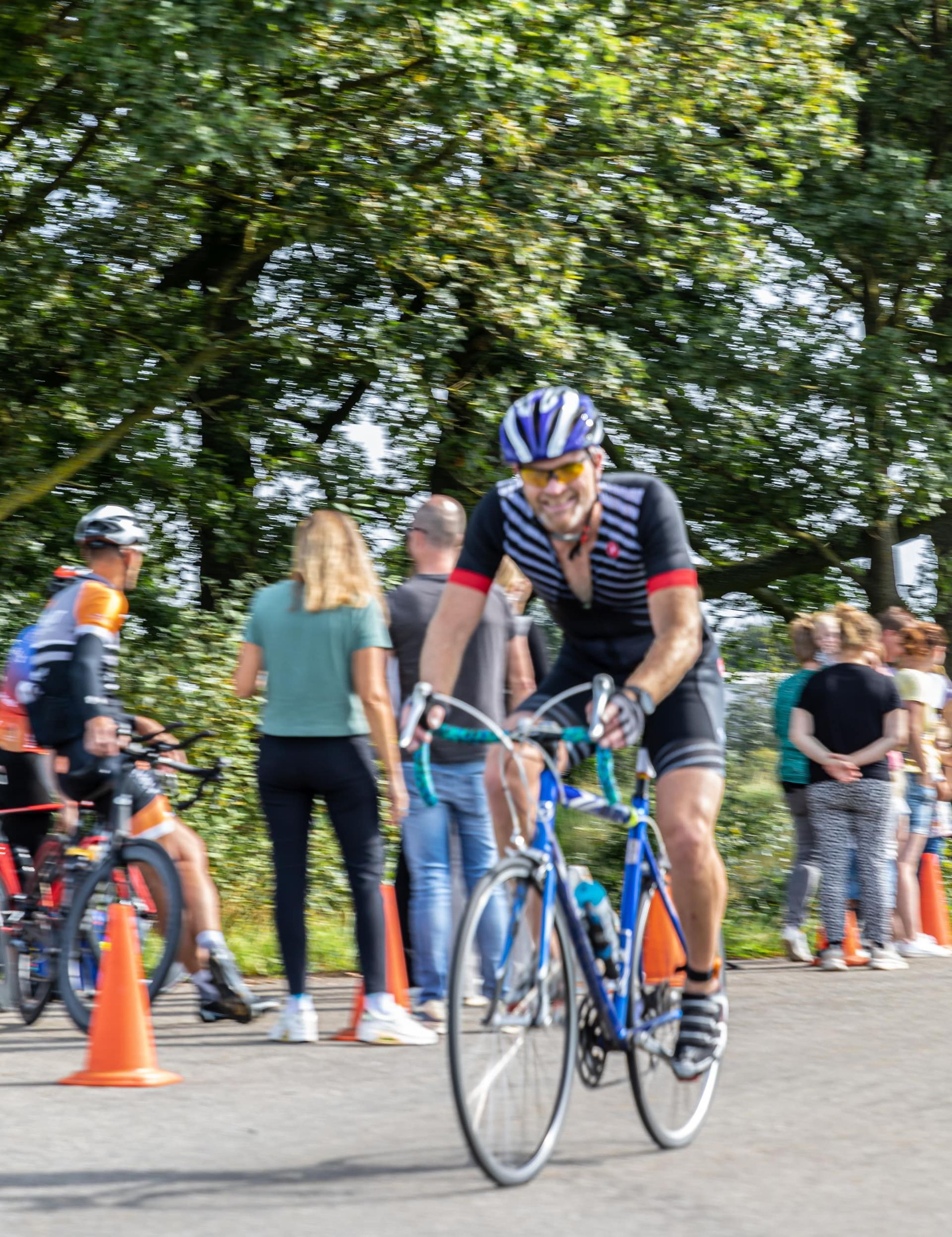 Een man fietst over een weg voor een menigte mensen.