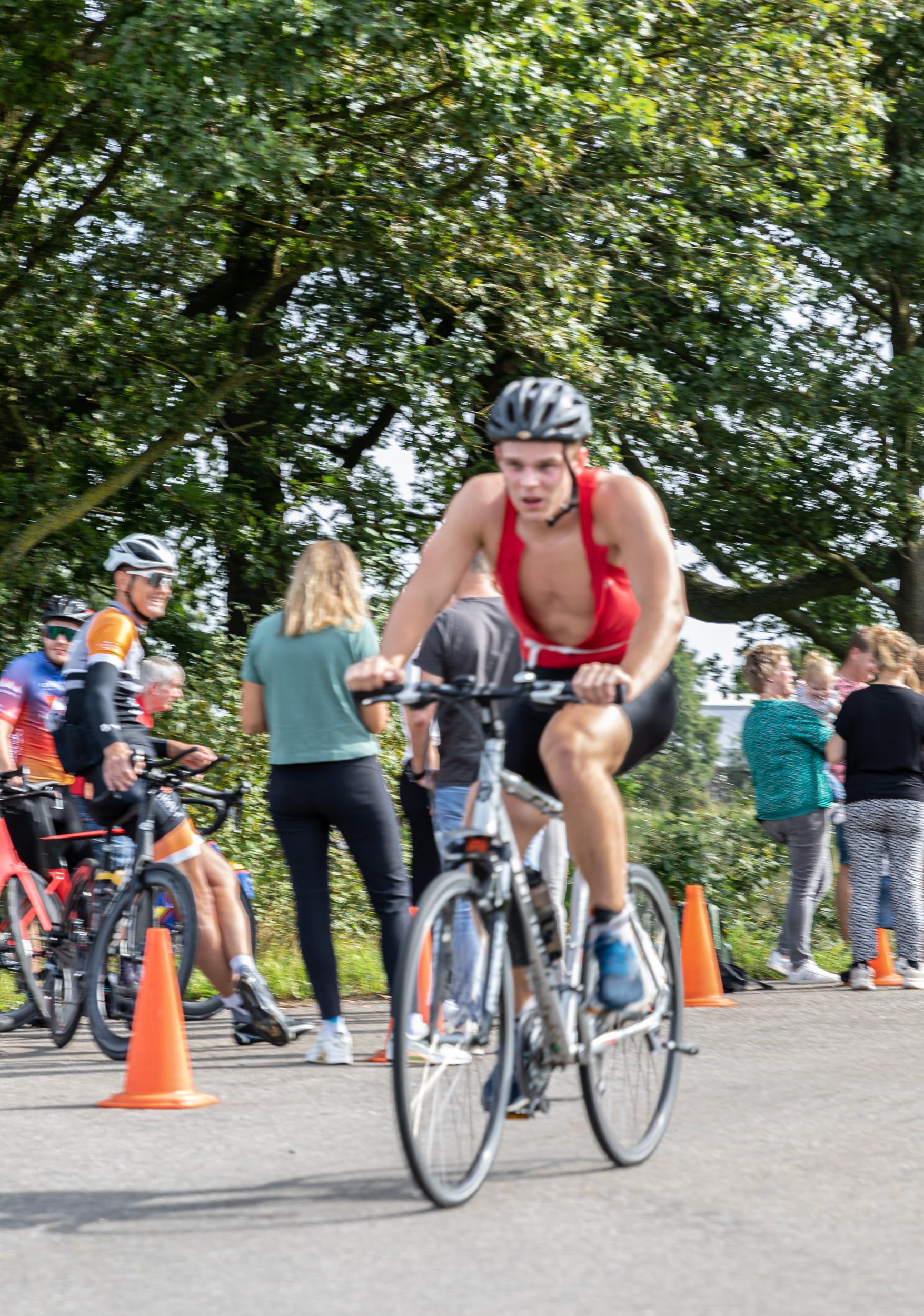 Een man met een helm rijdt op een fiets op de weg.