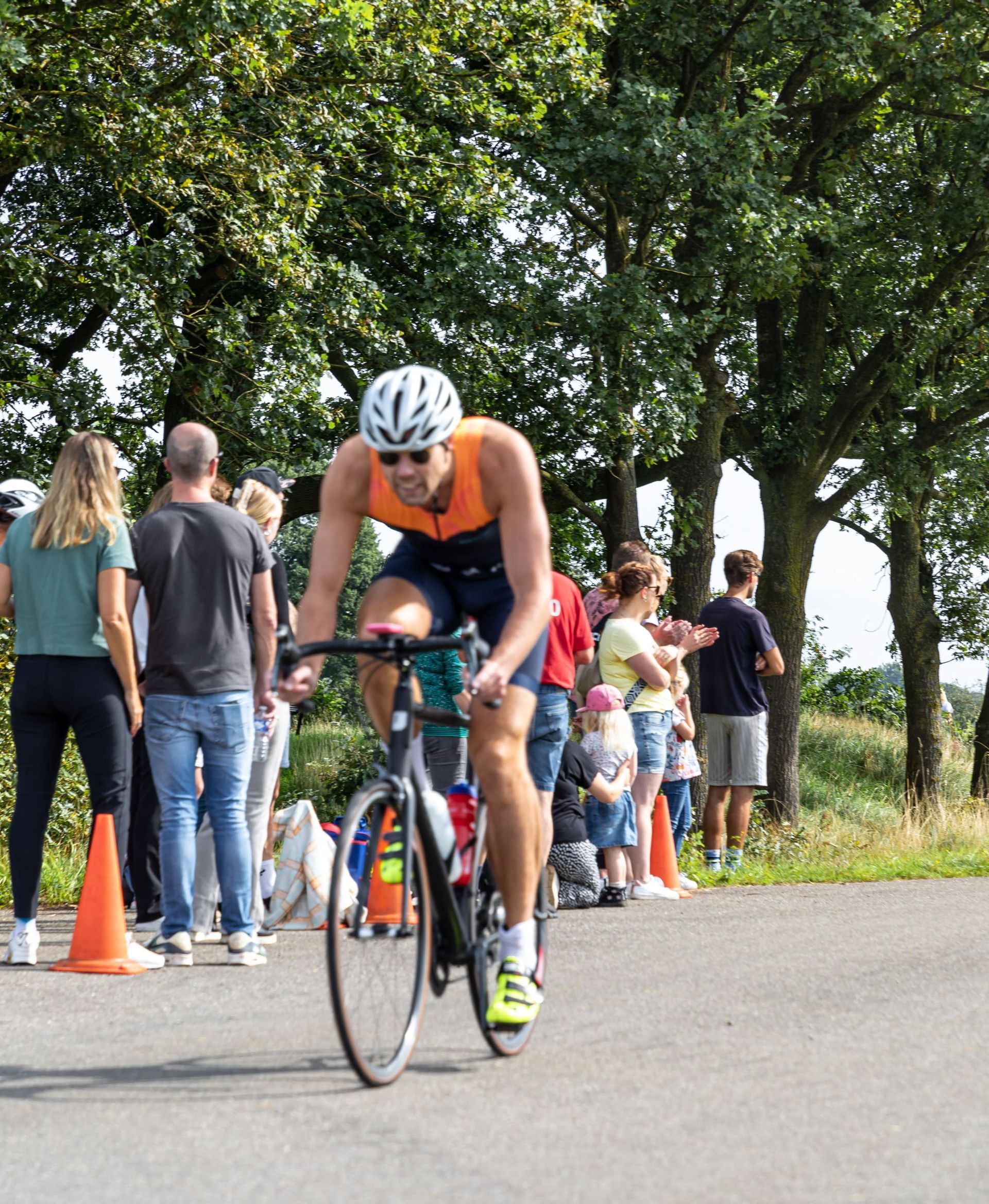 Een man met een helm rijdt op een fiets over een weg