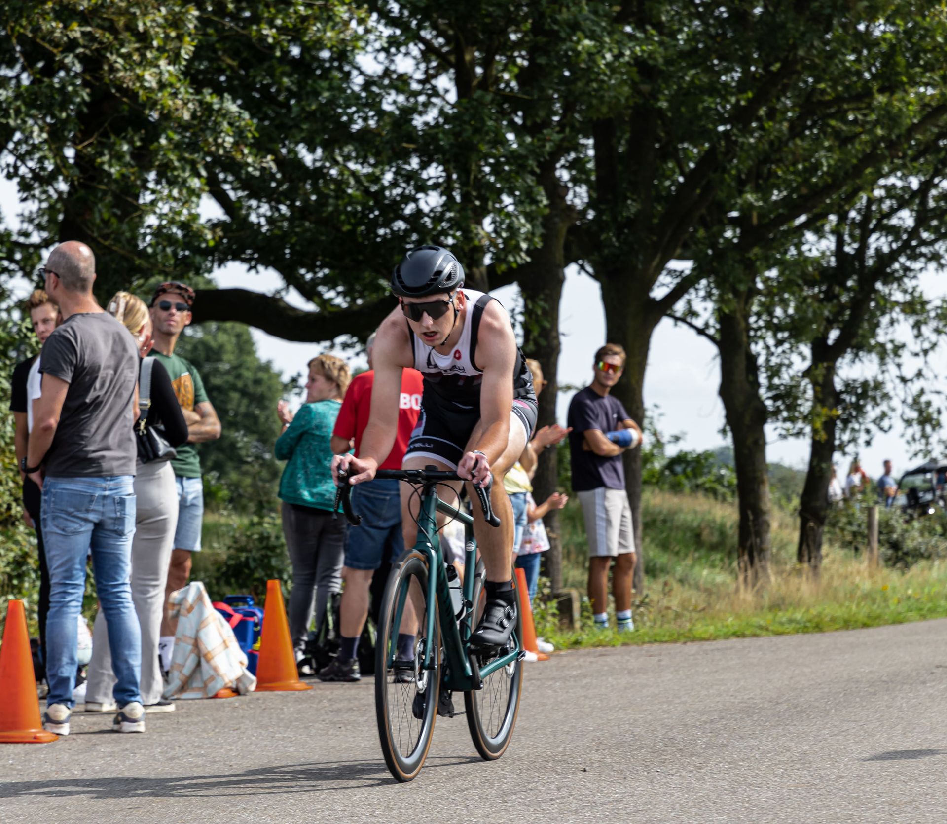Een man fietst over een weg voor een menigte mensen