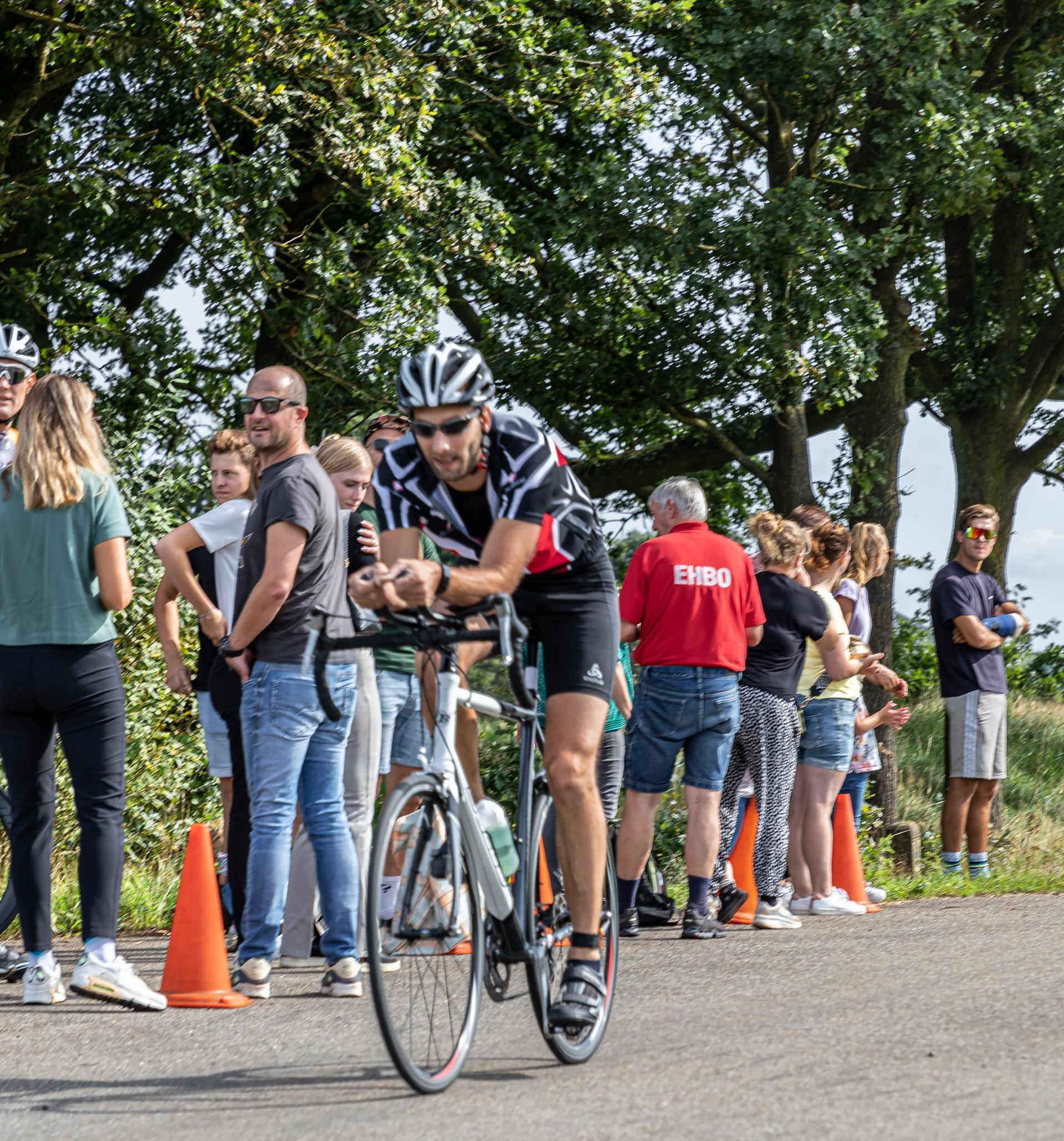 Een man fietst over een weg voor een menigte mensen.