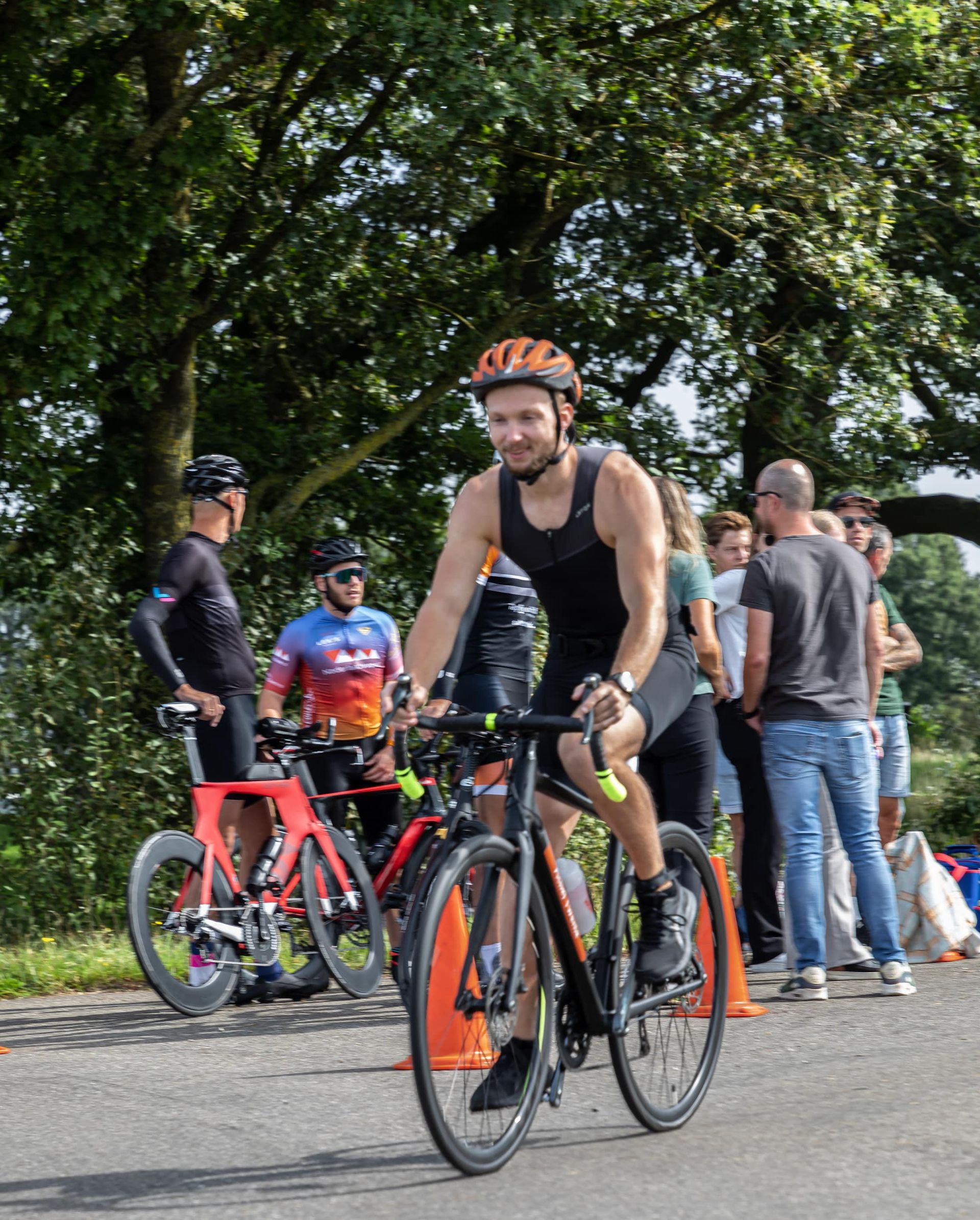 Een man met een helm rijdt op een fiets op de weg.