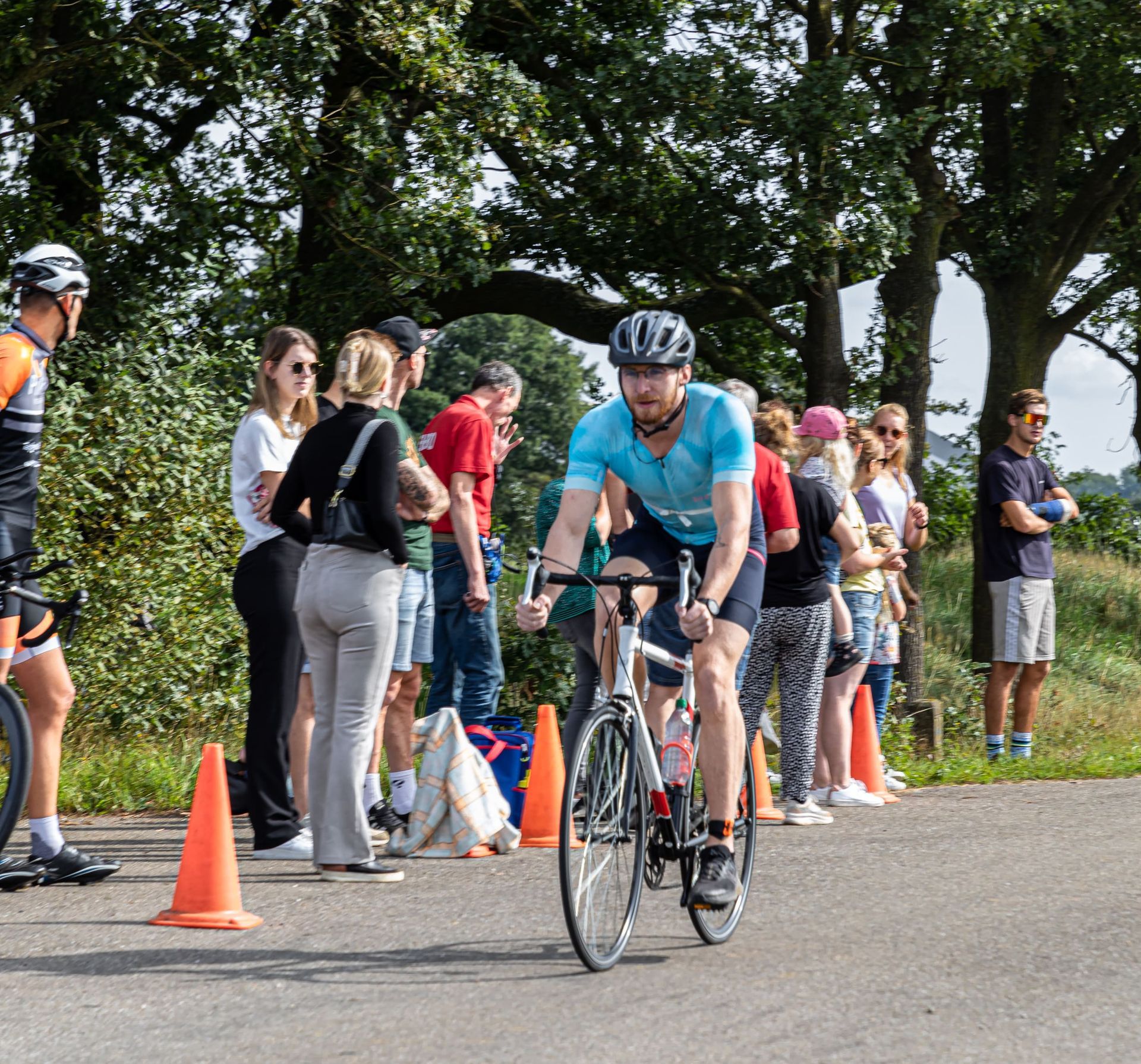 Een man met een helm rijdt op een fiets over een weg