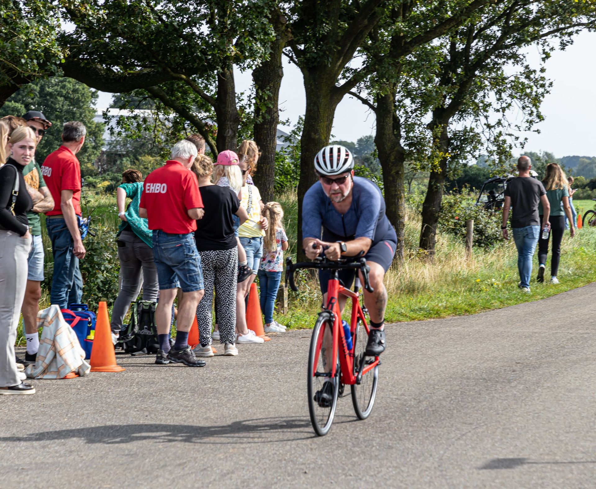 Een man met een helm rijdt op een fiets over de weg.