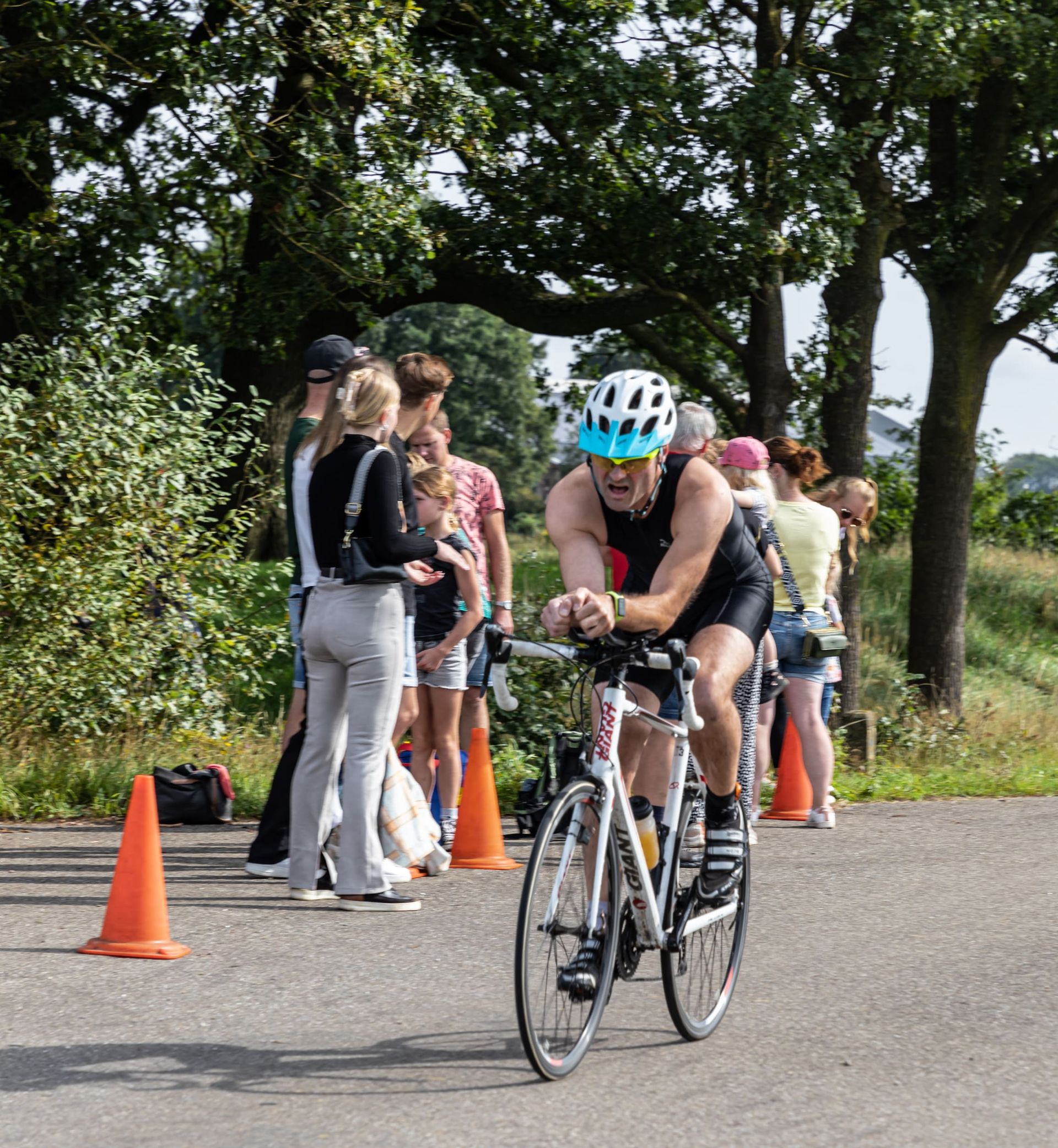 Een man met een helm rijdt op een fiets over een weg