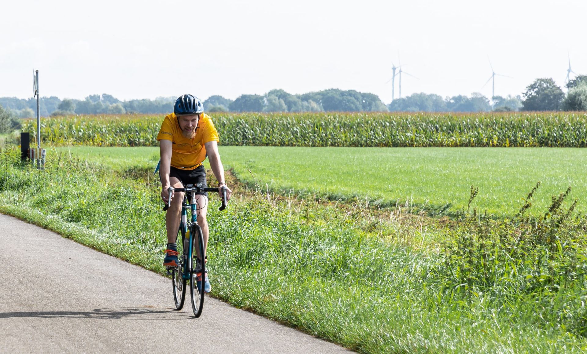 Een man fietst over een weg naast een veld.
