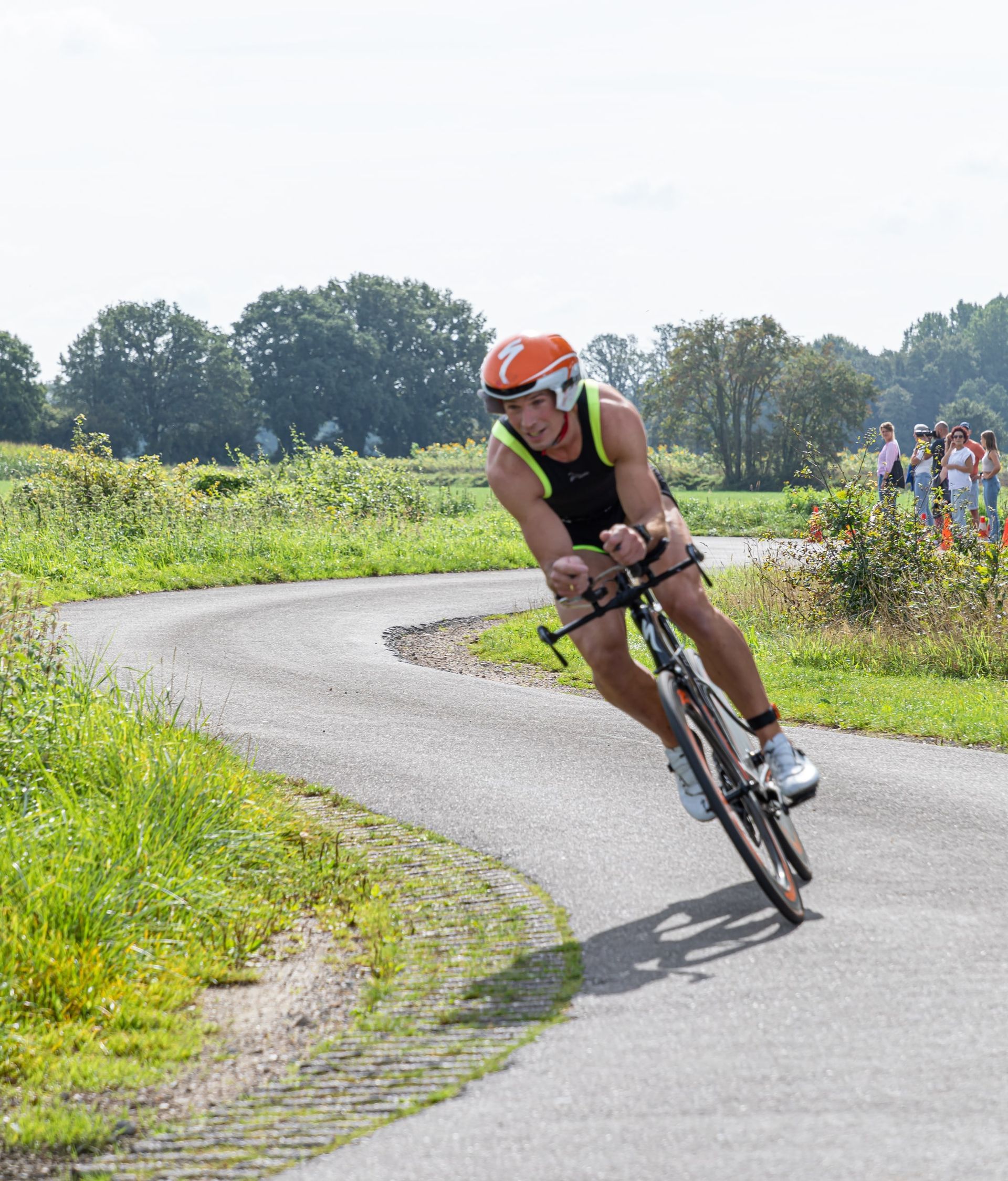 Een man met een helm rijdt op een fiets over een weg