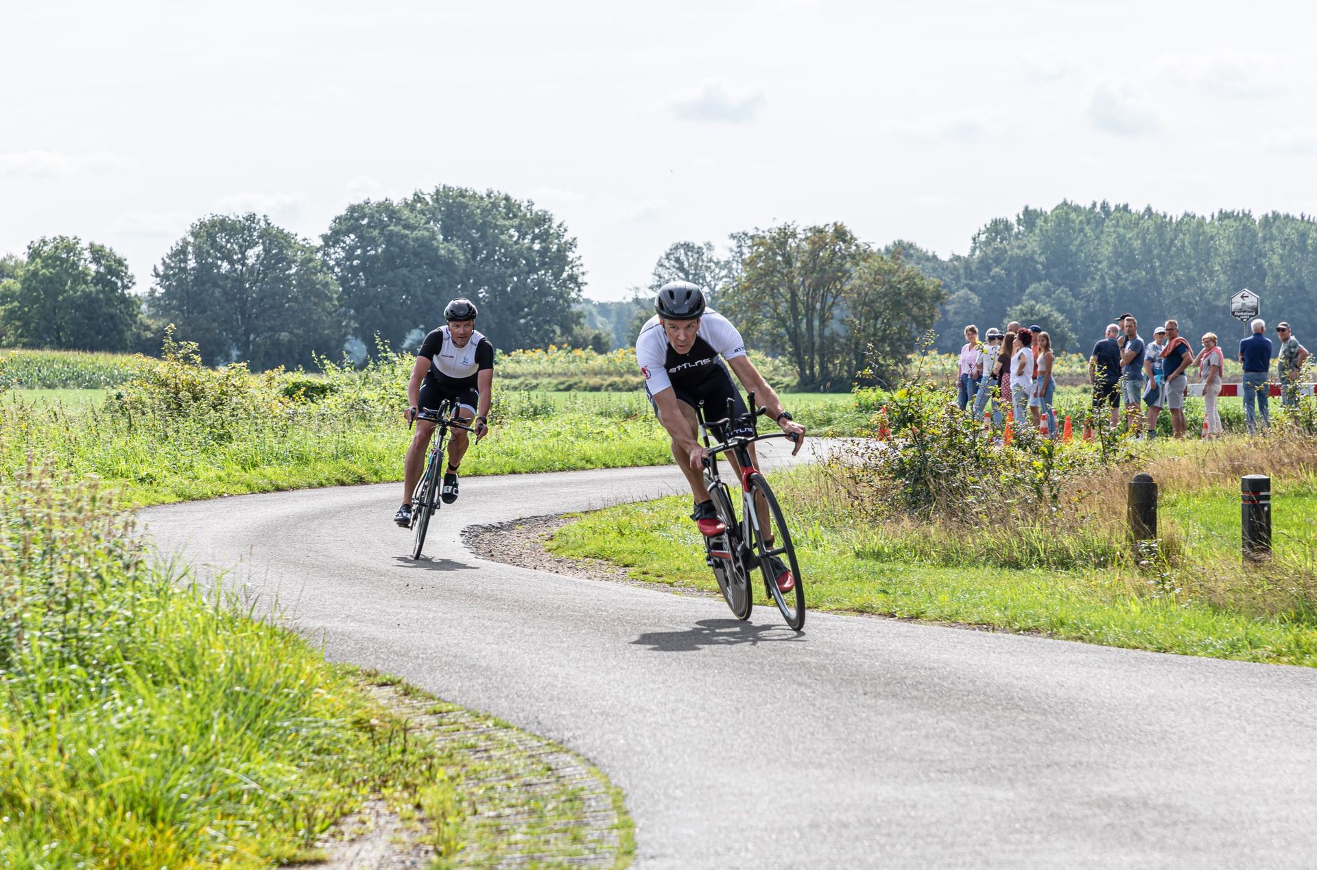 Twee mannen fietsen over een bochtige weg.