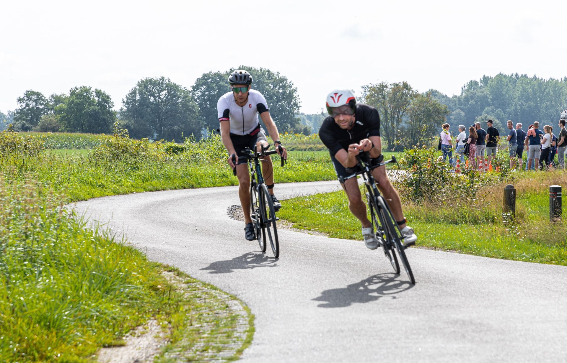 Twee mannen fietsen over een bochtige weg.