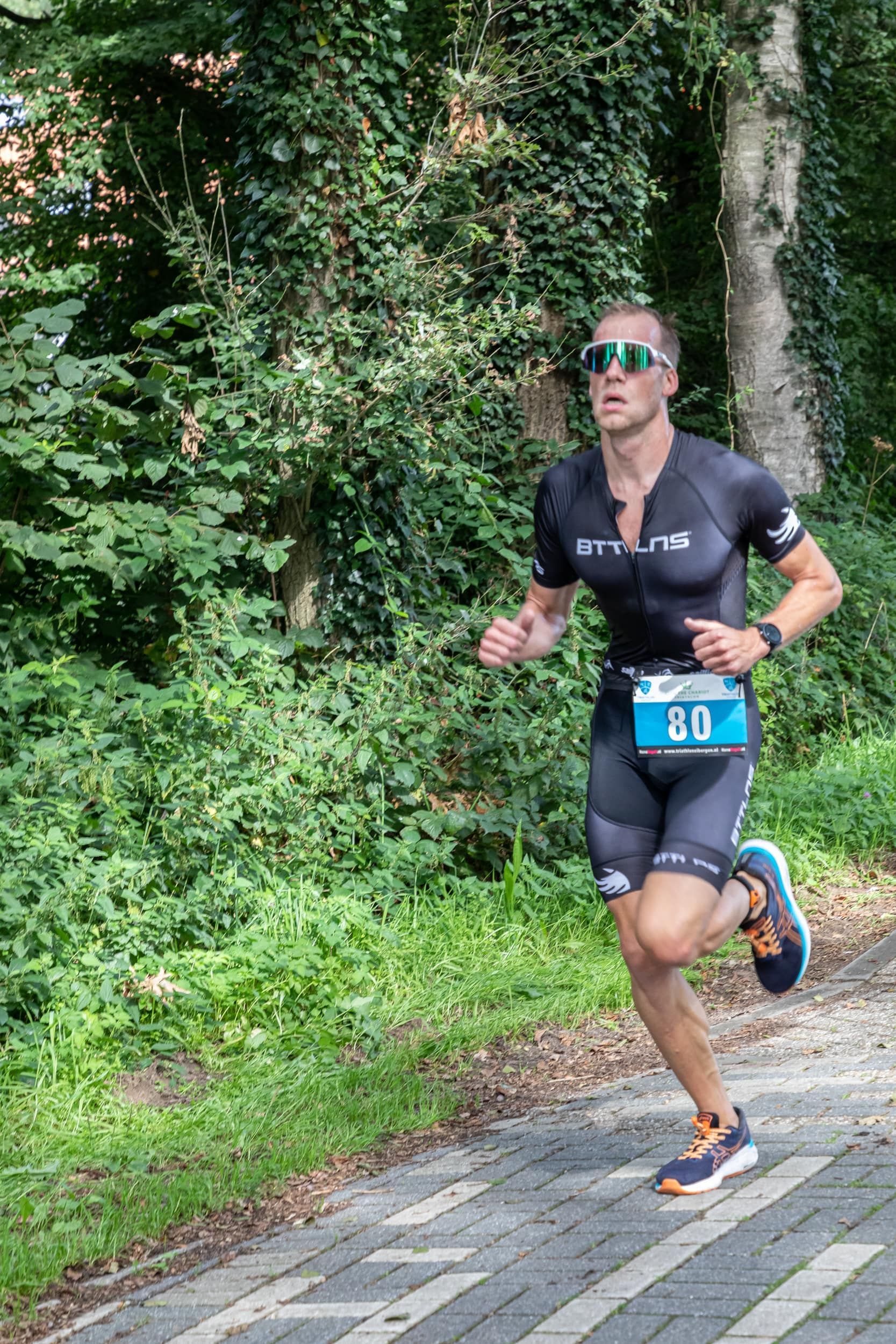 Een man rent over een stenen weg in het bos.