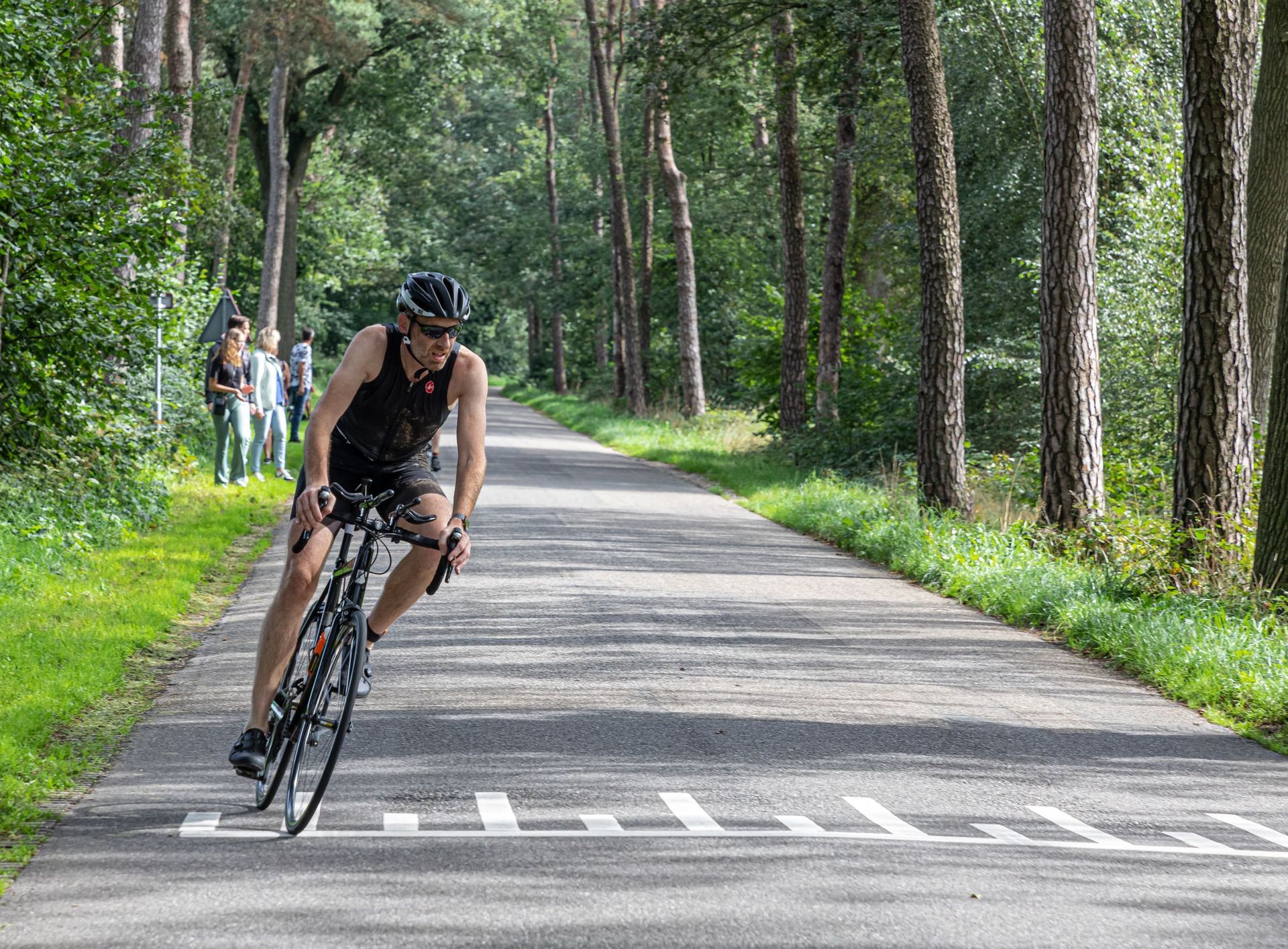 Een man fietst over een weg in het bos.
